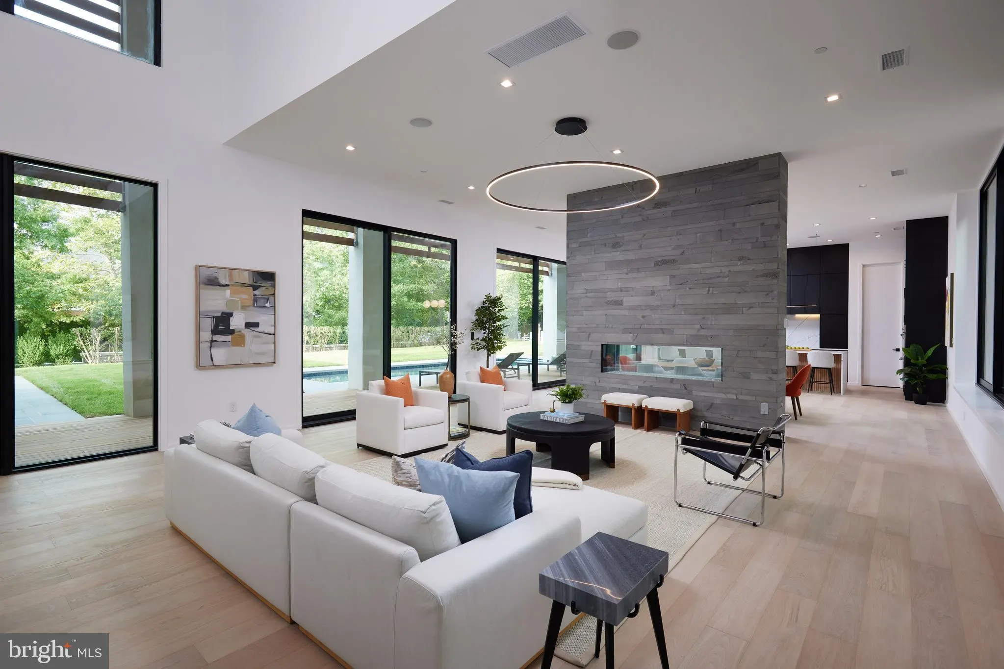 Open living, dining, and kitchen with floor-to-ceiling windows to the yard