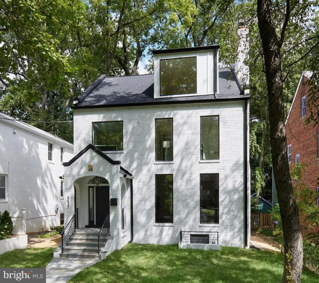 Modern white brick house with black roof and metal railing entry