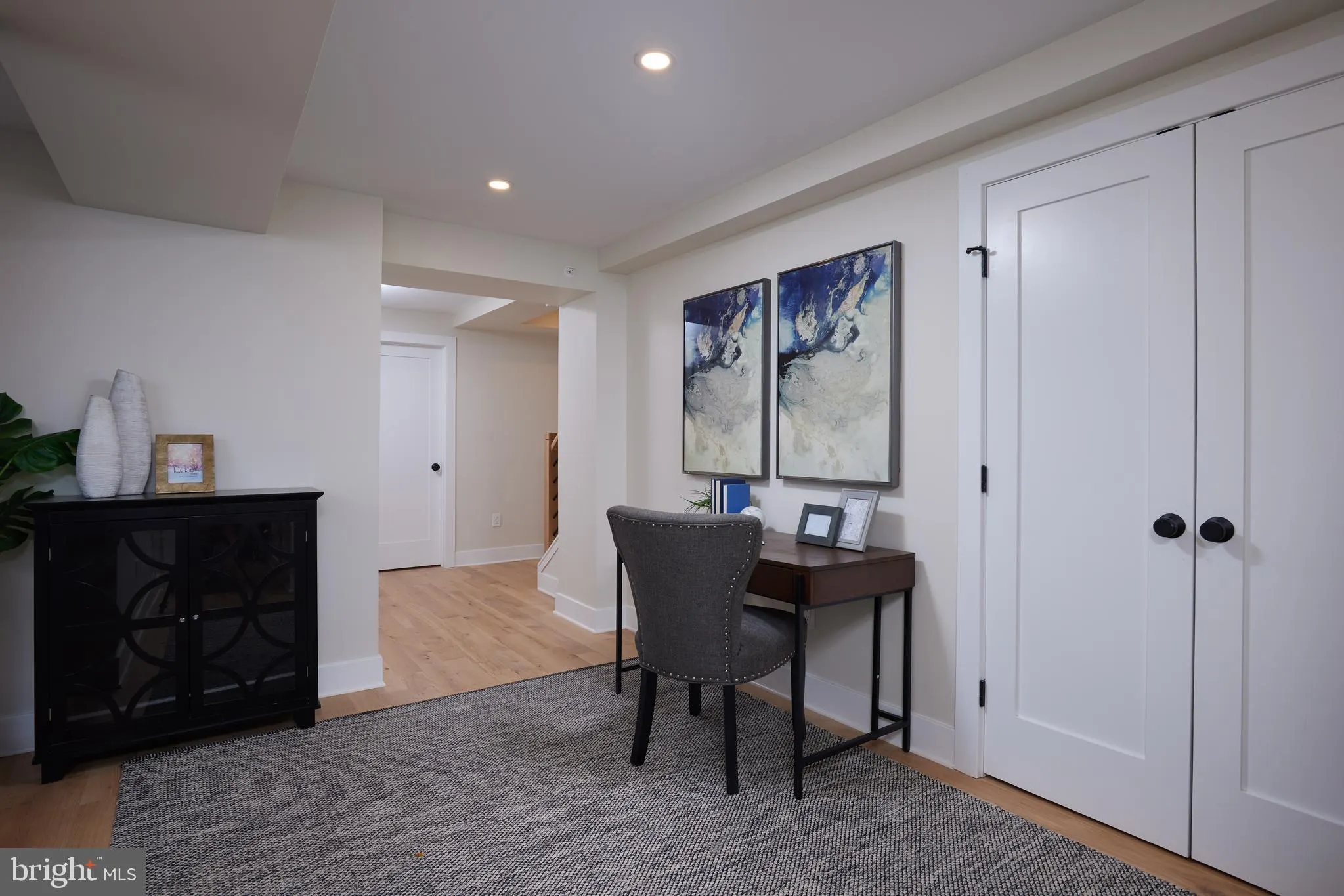Home office with black cabinet, desk, and white closet doors