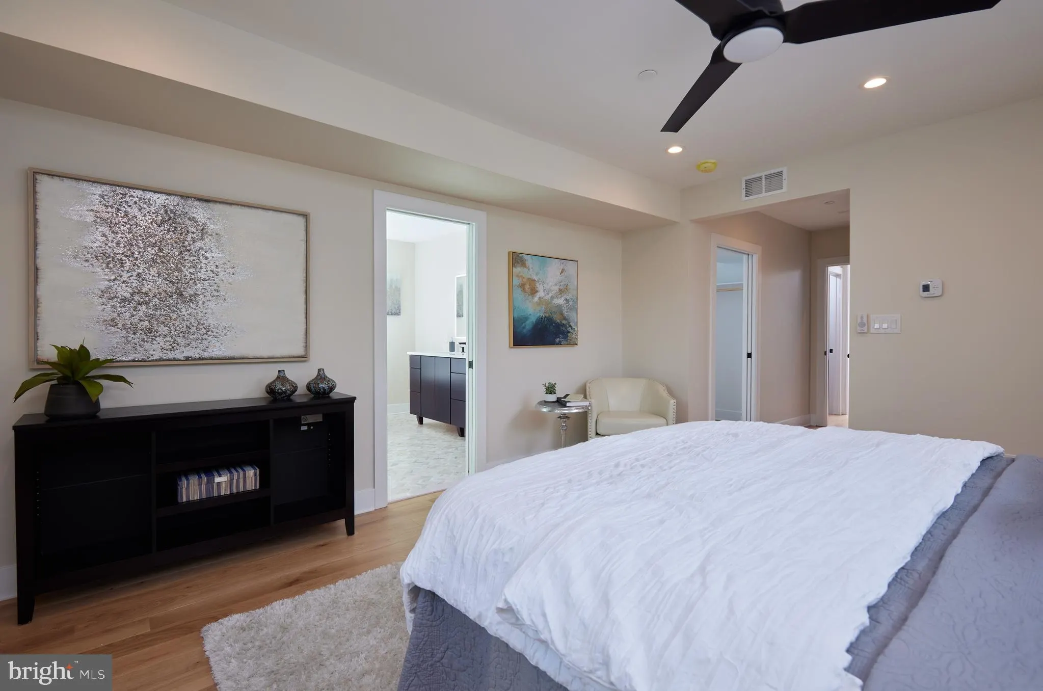Primary bedroom with black dresser and ensuite bathroom access
