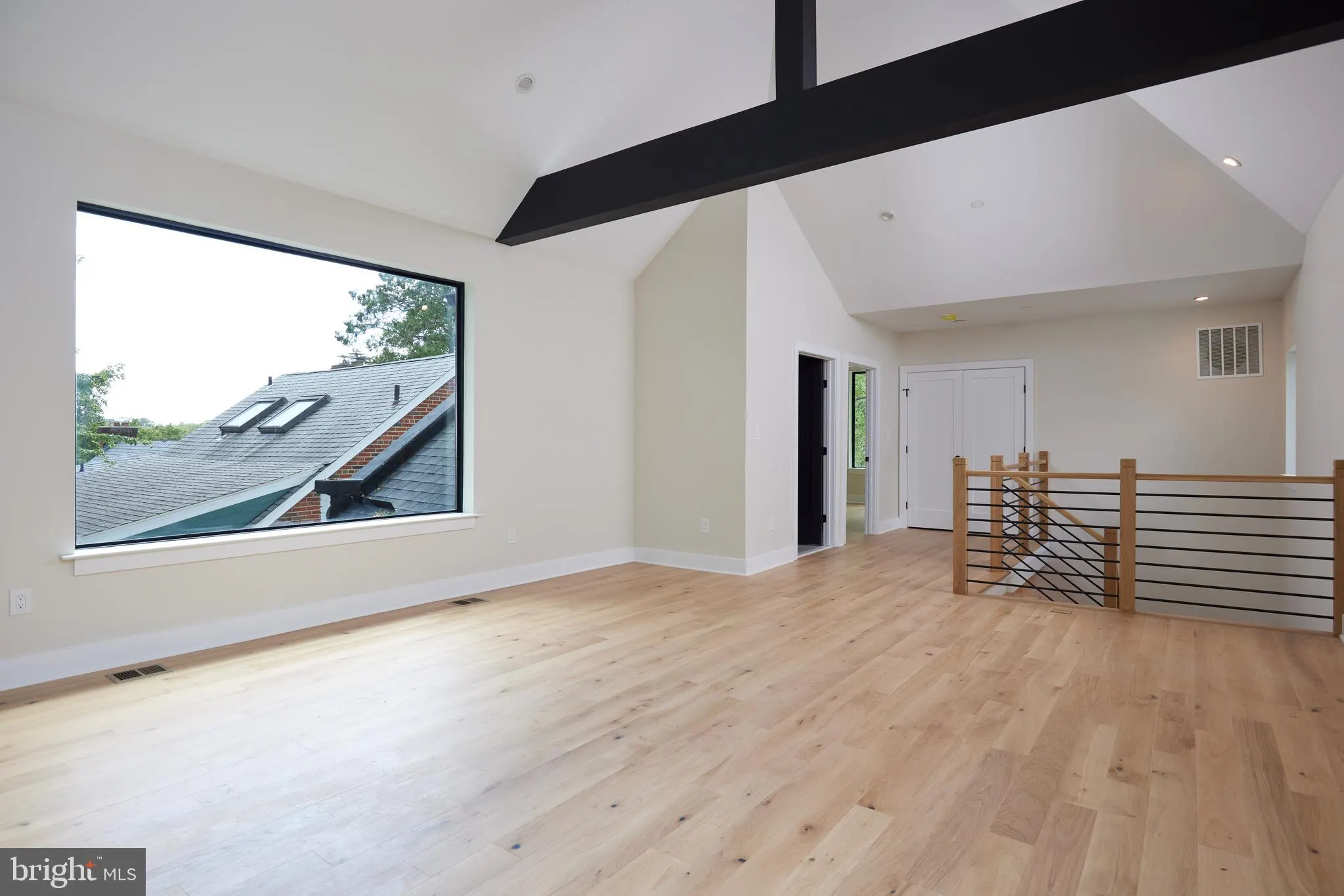 Loft space with black beam ceiling and wood metal railing