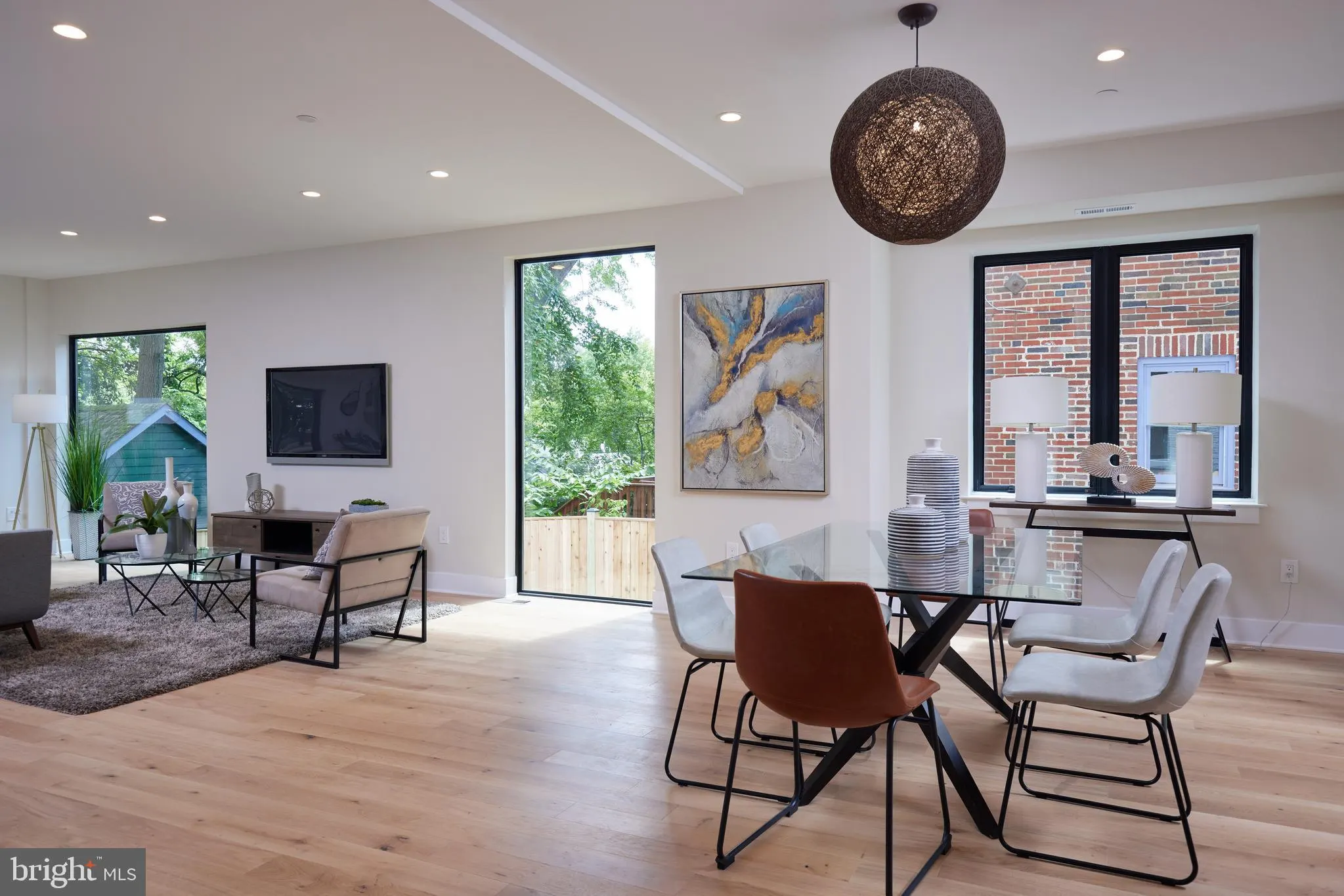 Open living and dining area with globe pendant and brick accent wall