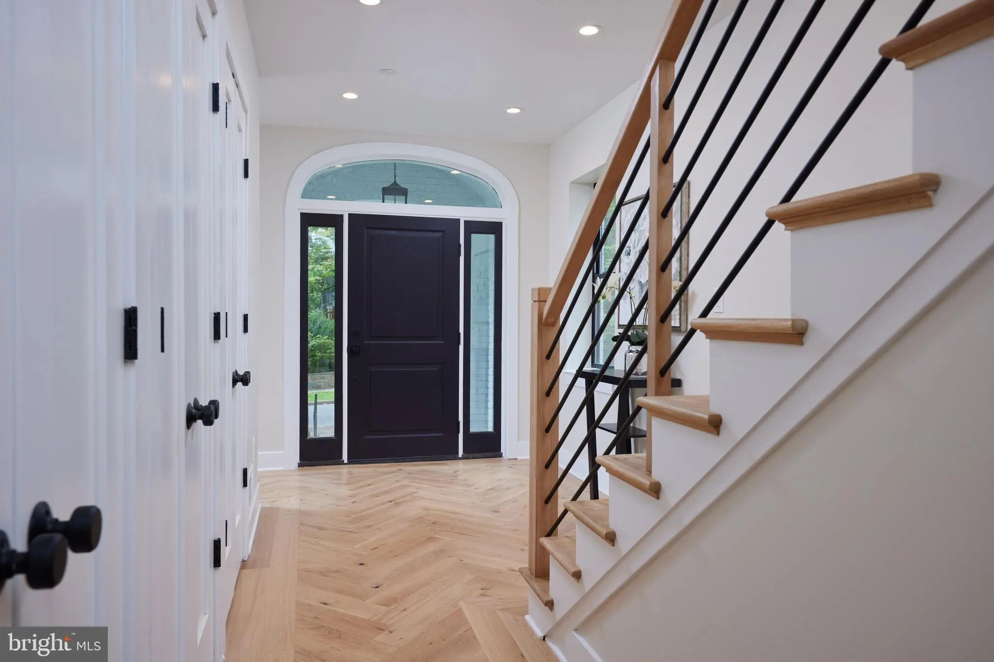 Foyer with black front door and wooden stair railing