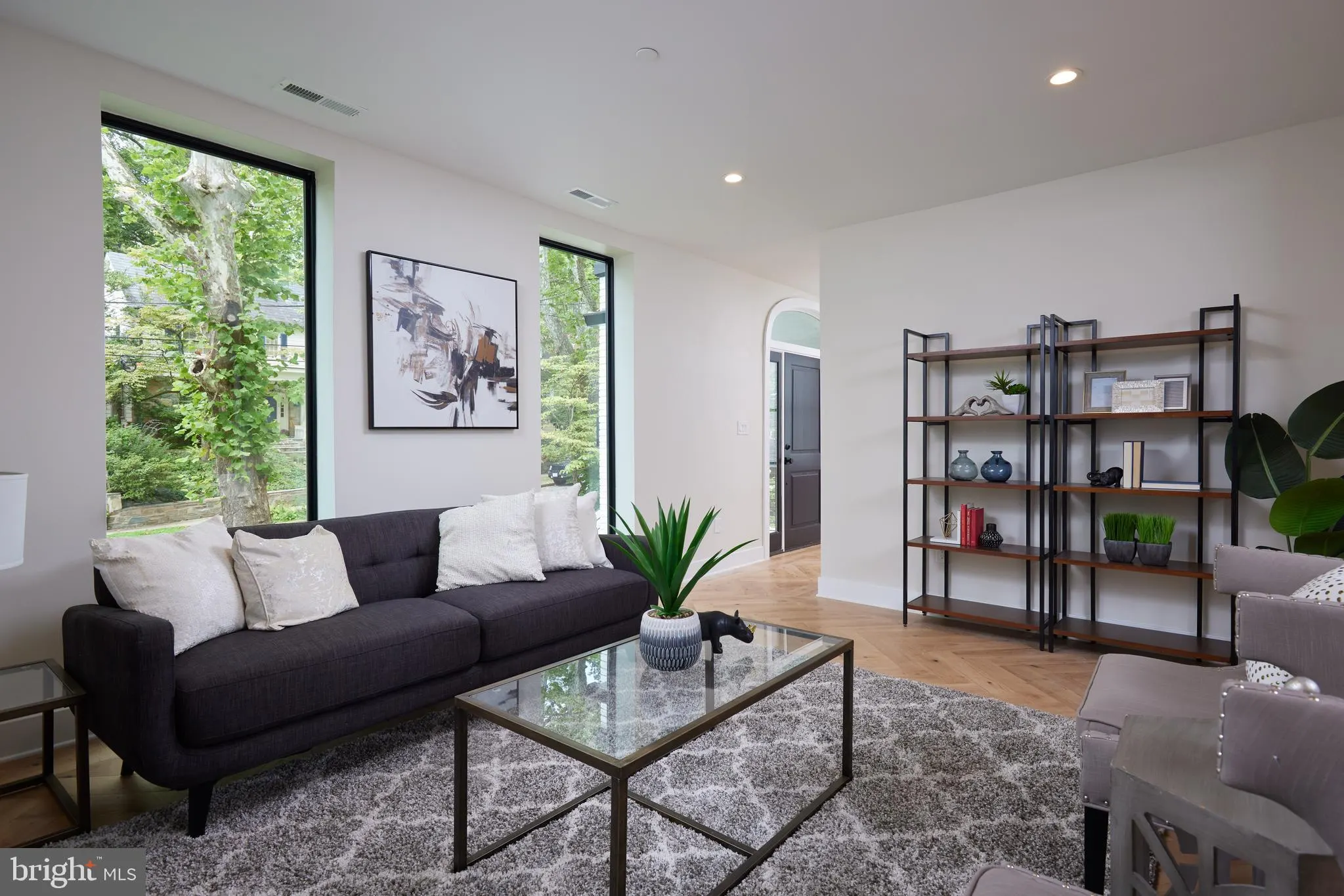 Living room with black sofa, glass coffee table, and metal shelving unit