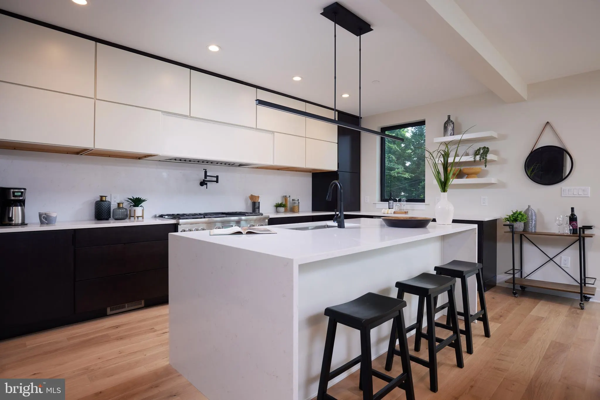 Modern kitchen with white island, black stools, and stainless steel appliances
