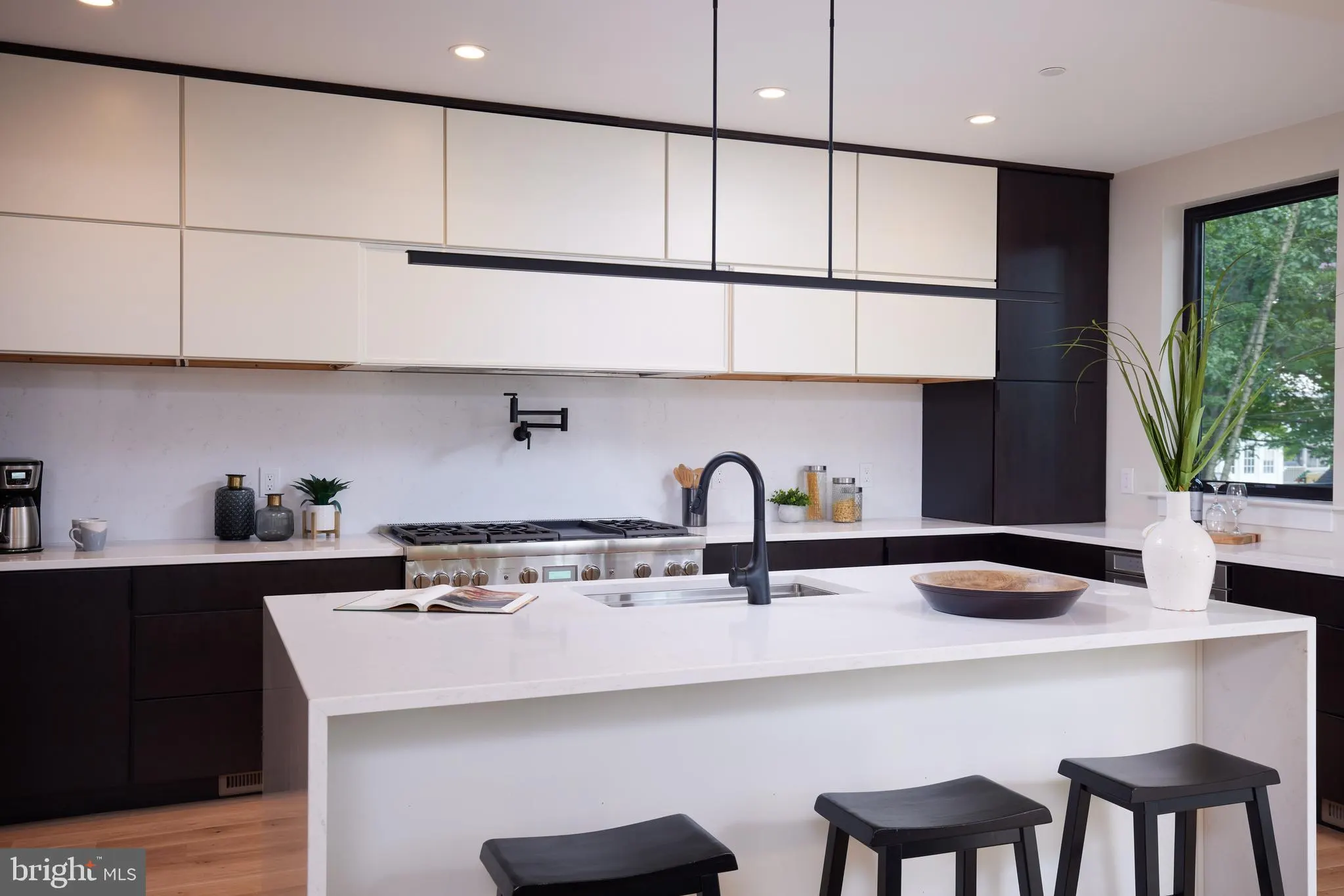 Kitchen with black and white cabinetry, gas range, and island seating