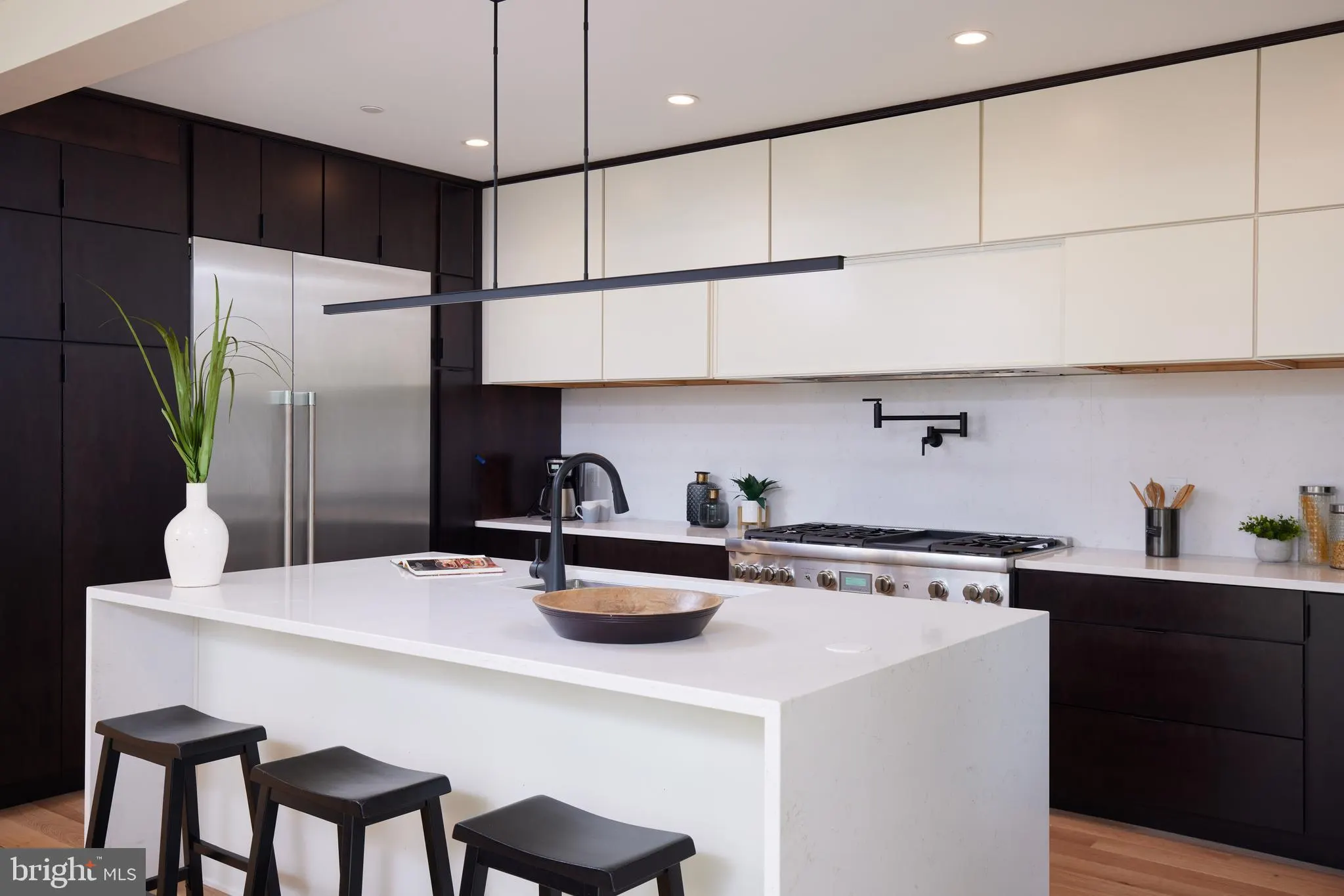 Contemporary kitchen featuring white island, stainless refrigerator, and gas cooktop