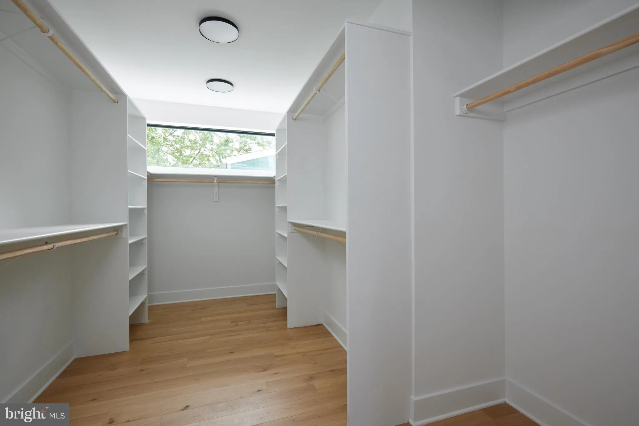 Walk-in closet with built-in shelving, wooden rods, clerestory window