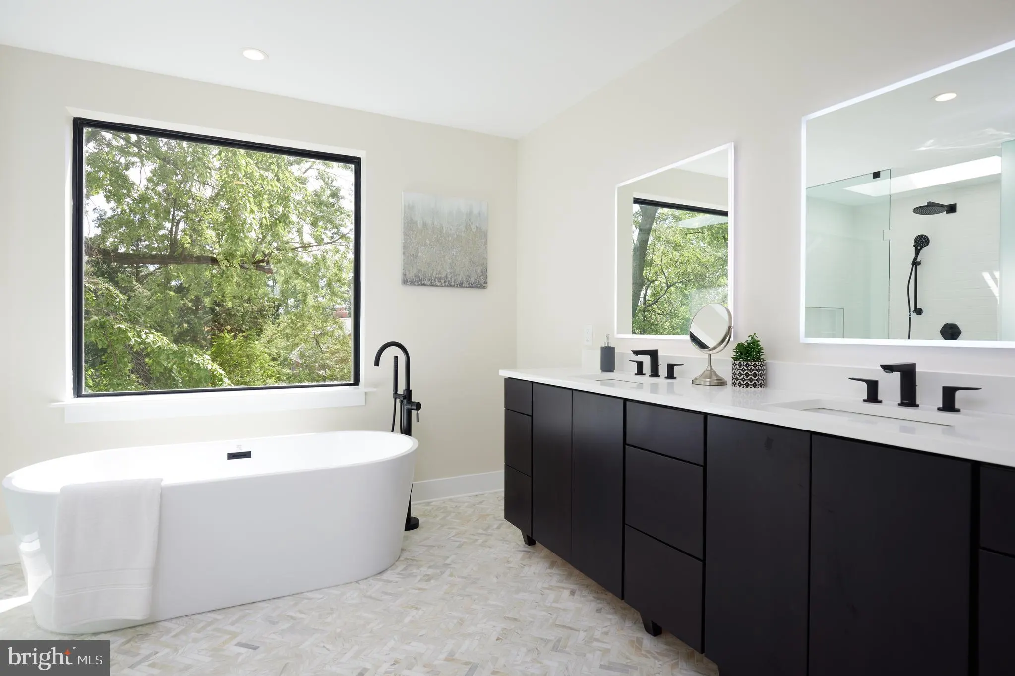 Primary bath with freestanding tub, black vanity, and large window