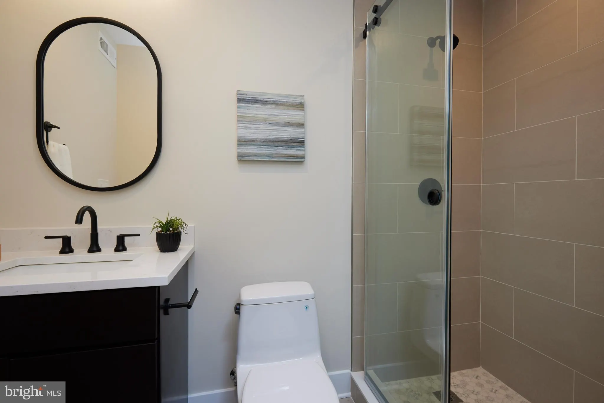 Bathroom with black vanity, oval mirror, and walk-in shower