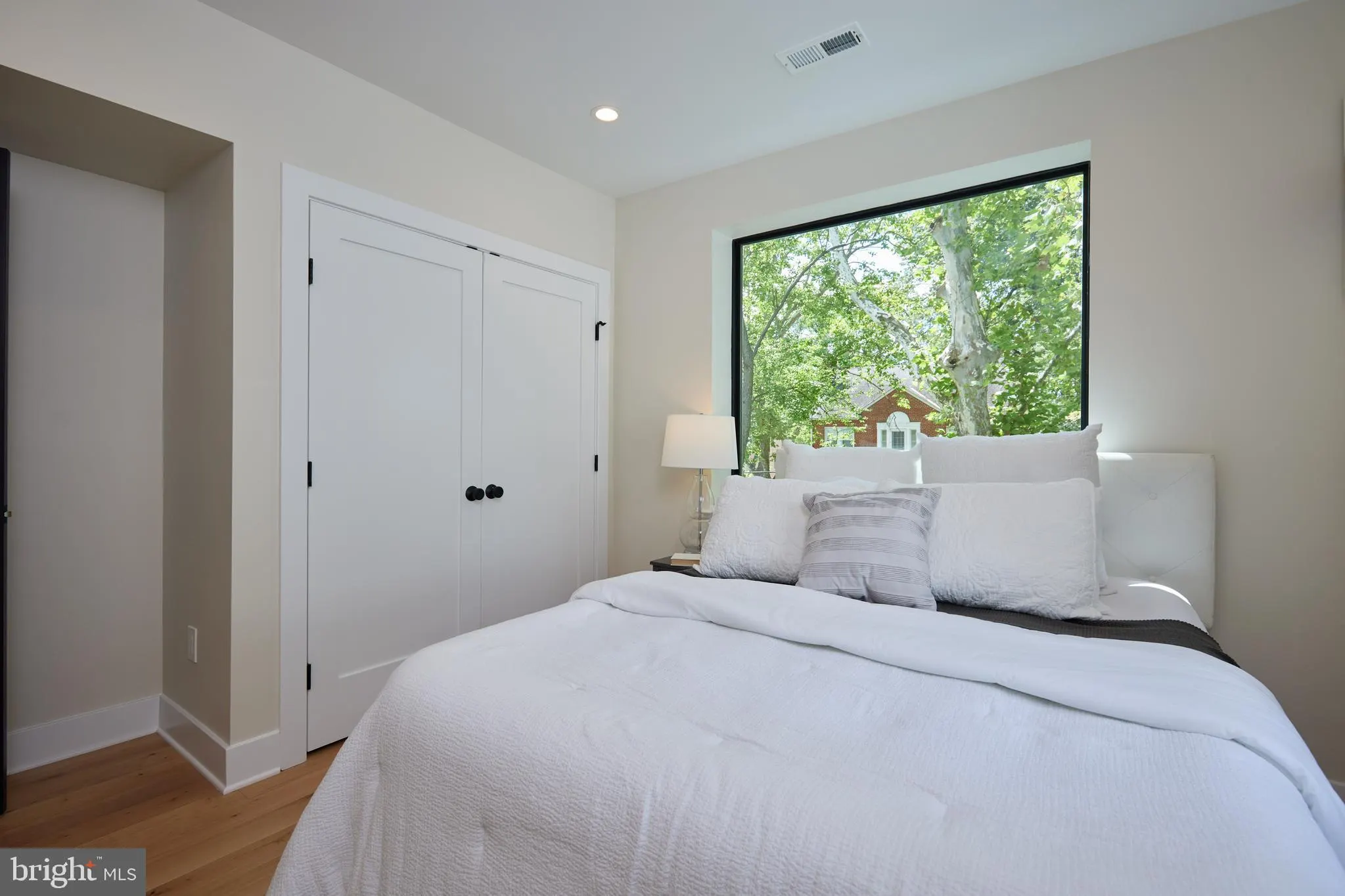 Bedroom with built-in white closets and large picture window