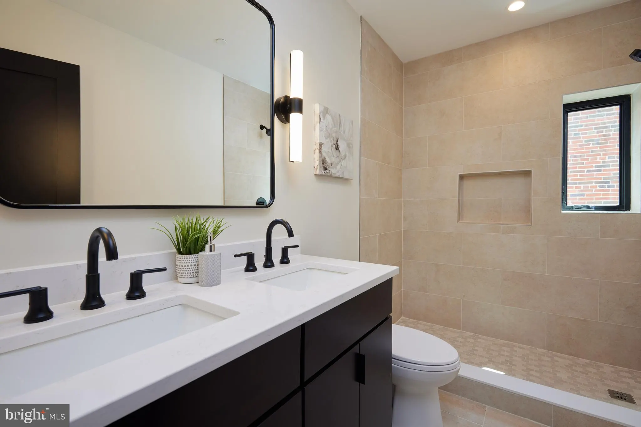 Primary bathroom with black vanity, white countertop, and tile shower
