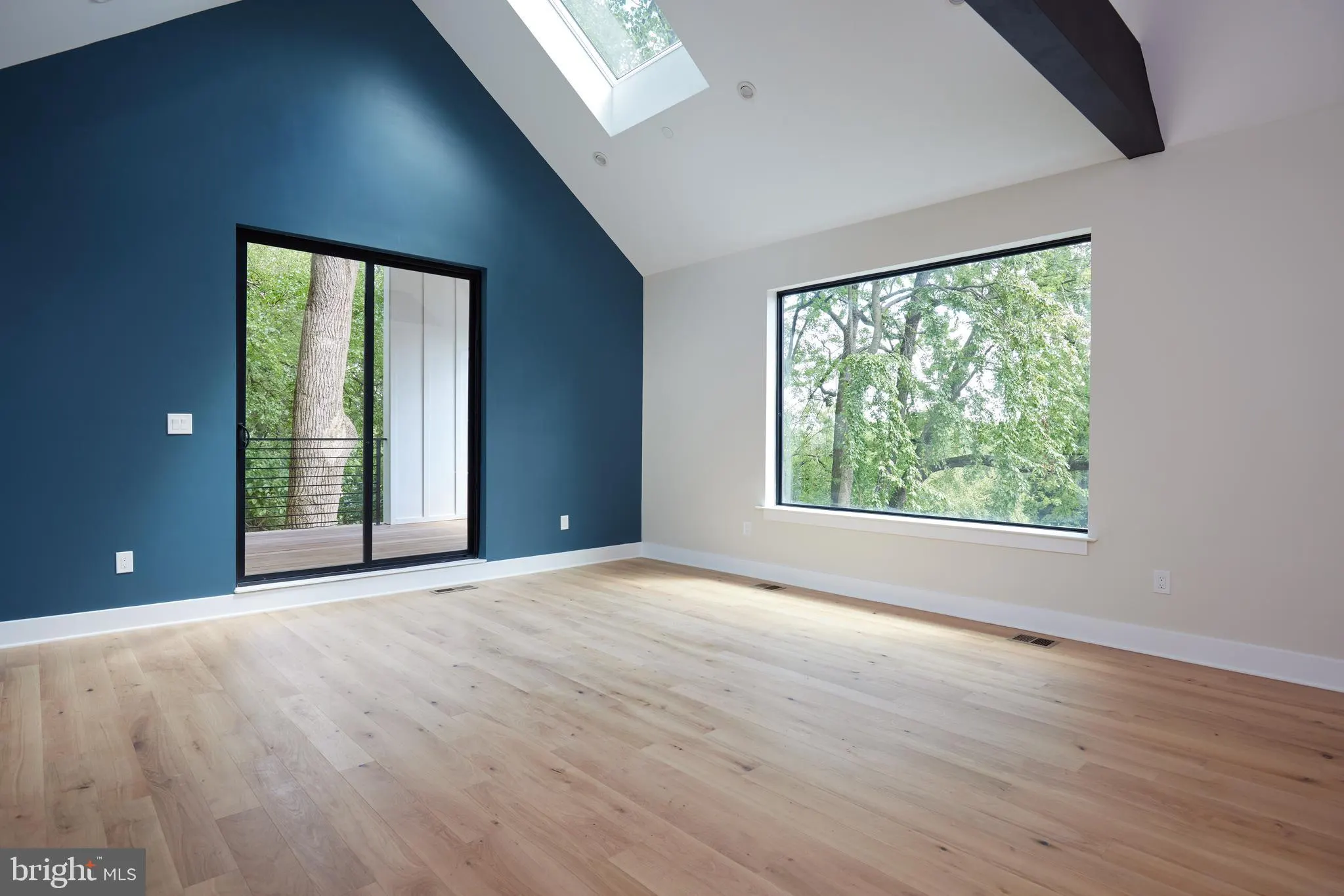 Room with blue accent wall, skylights, and wood flooring