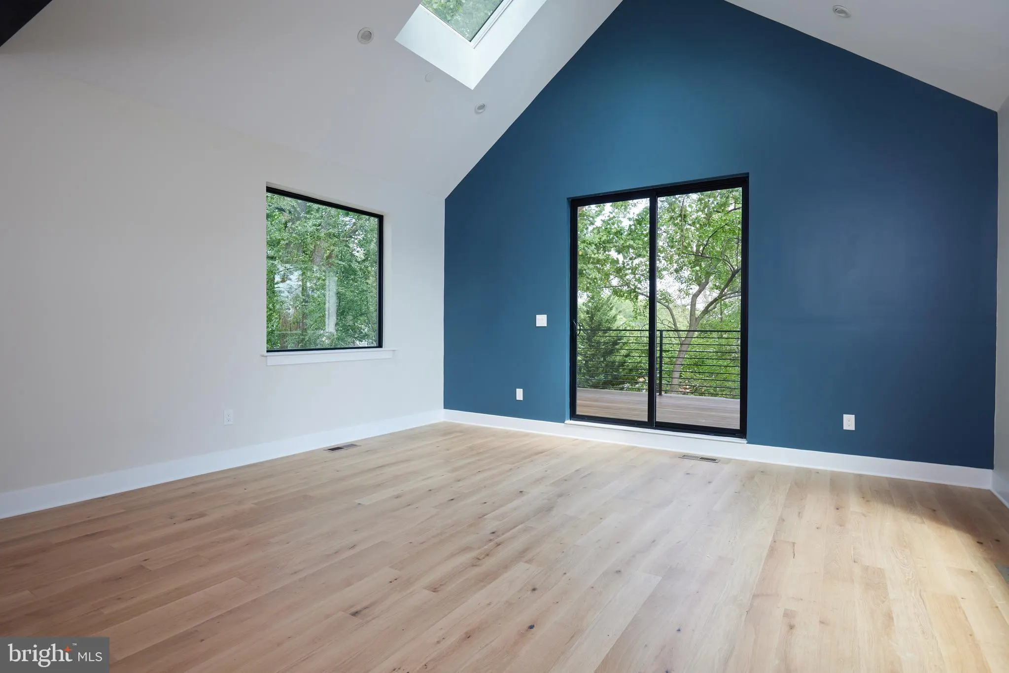 Open room with blue feature wall, glass doors to deck, and skylights