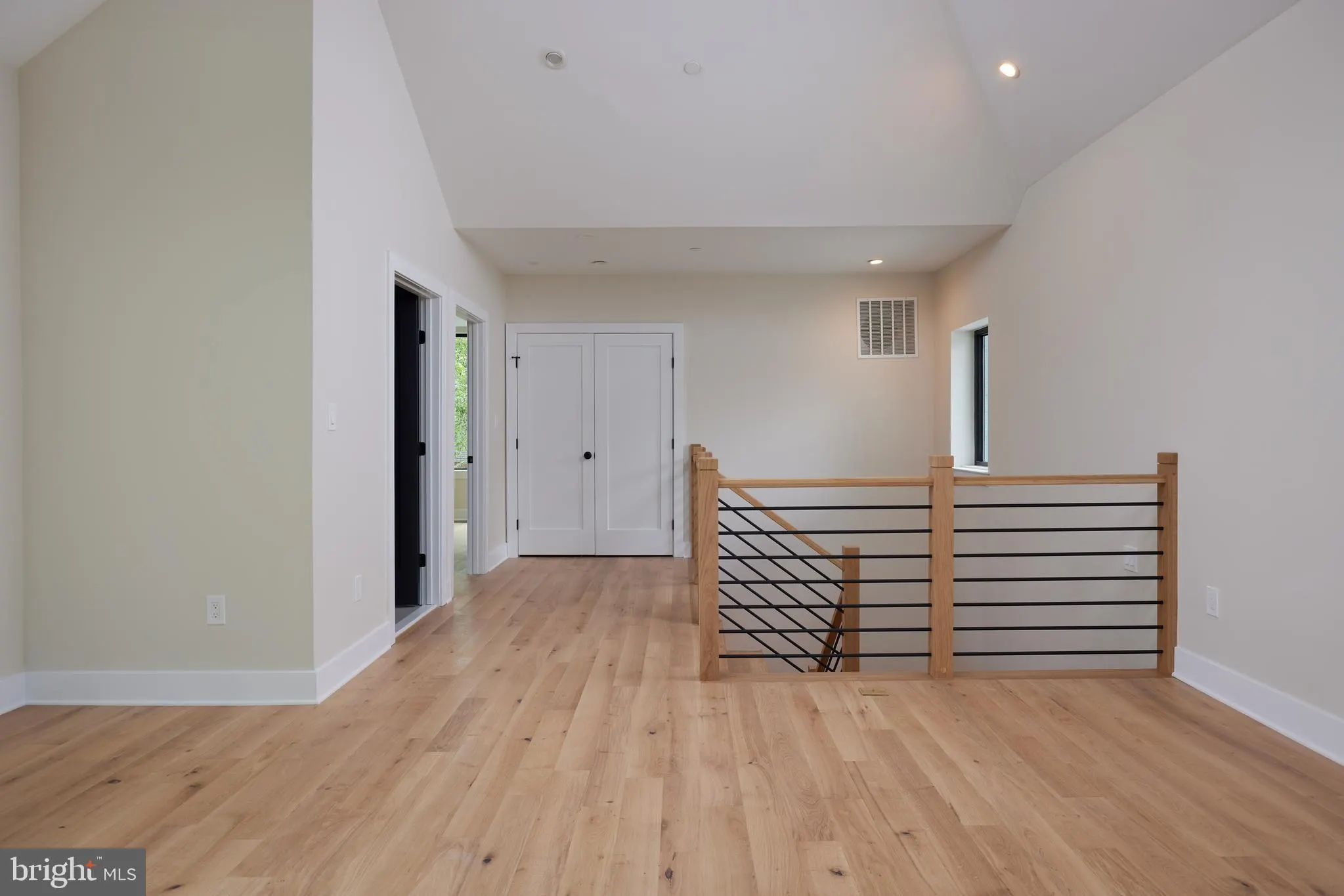 Upper level hallway with wood railing and white closet doors