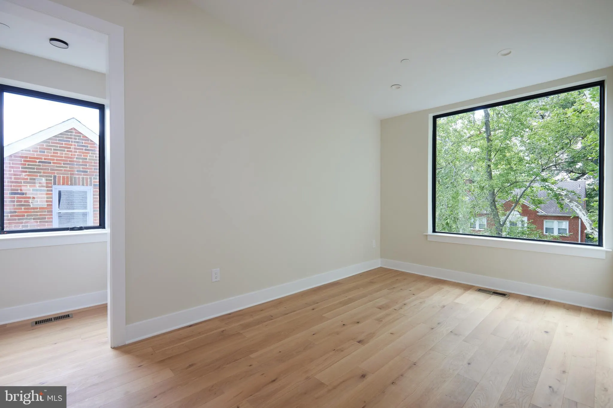 Bedroom with hardwood floors and large windows overlooking trees