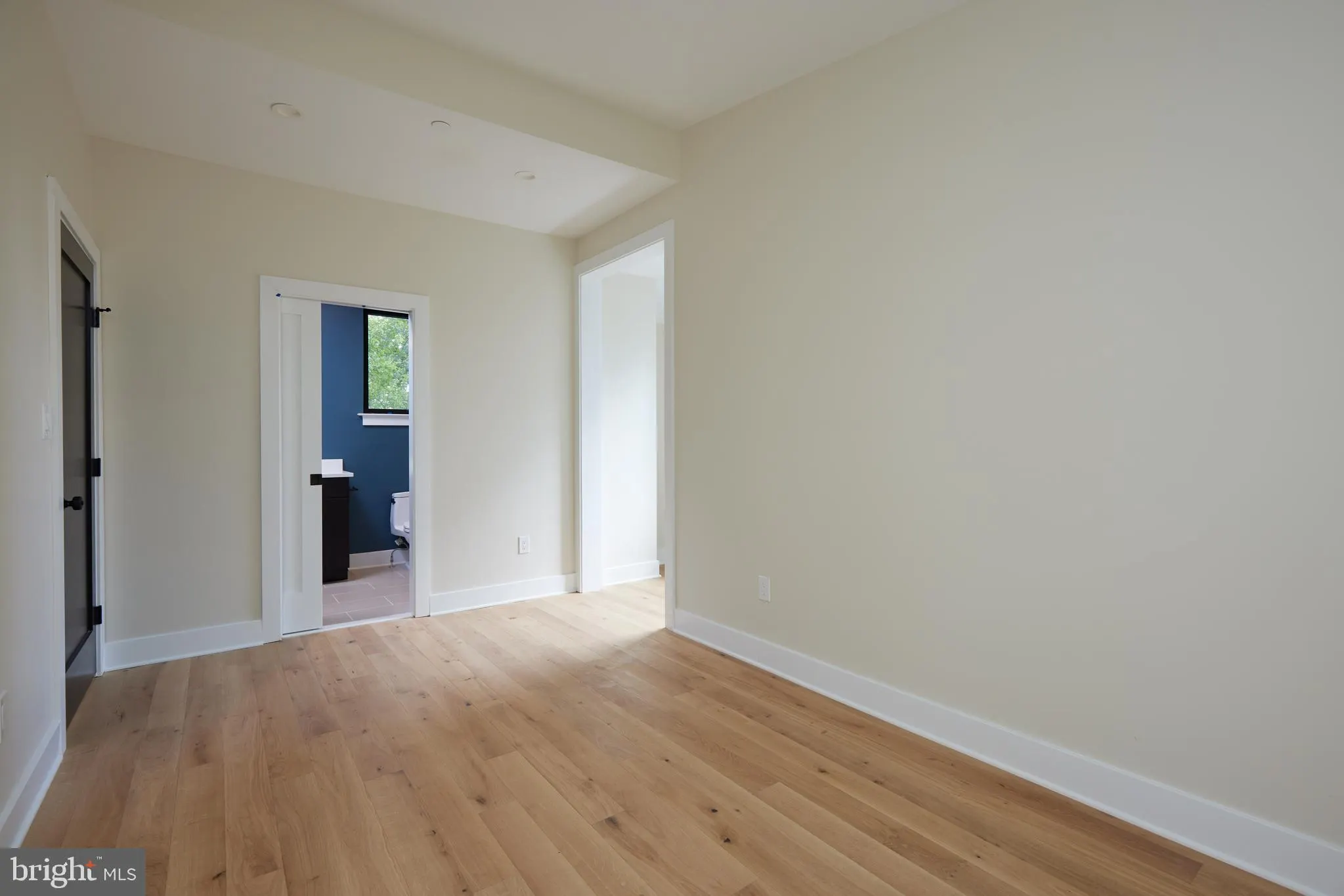 Bedroom with hardwood floors and doorway to ensuite bathroom