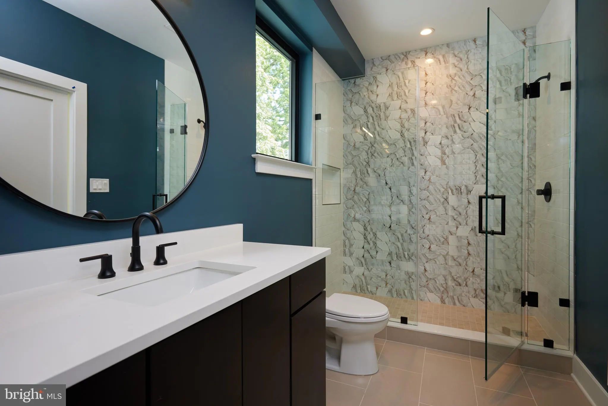 Bathroom with dark teal walls, marble shower, and black fixtures