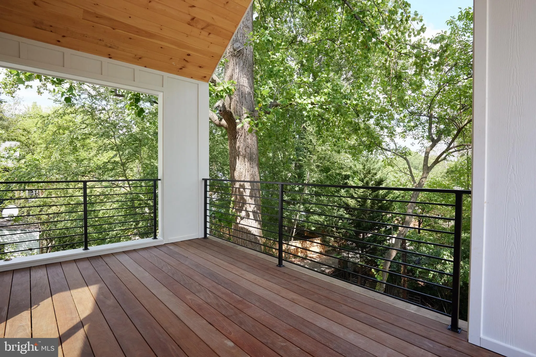Wooden deck with black metal railing and forest views