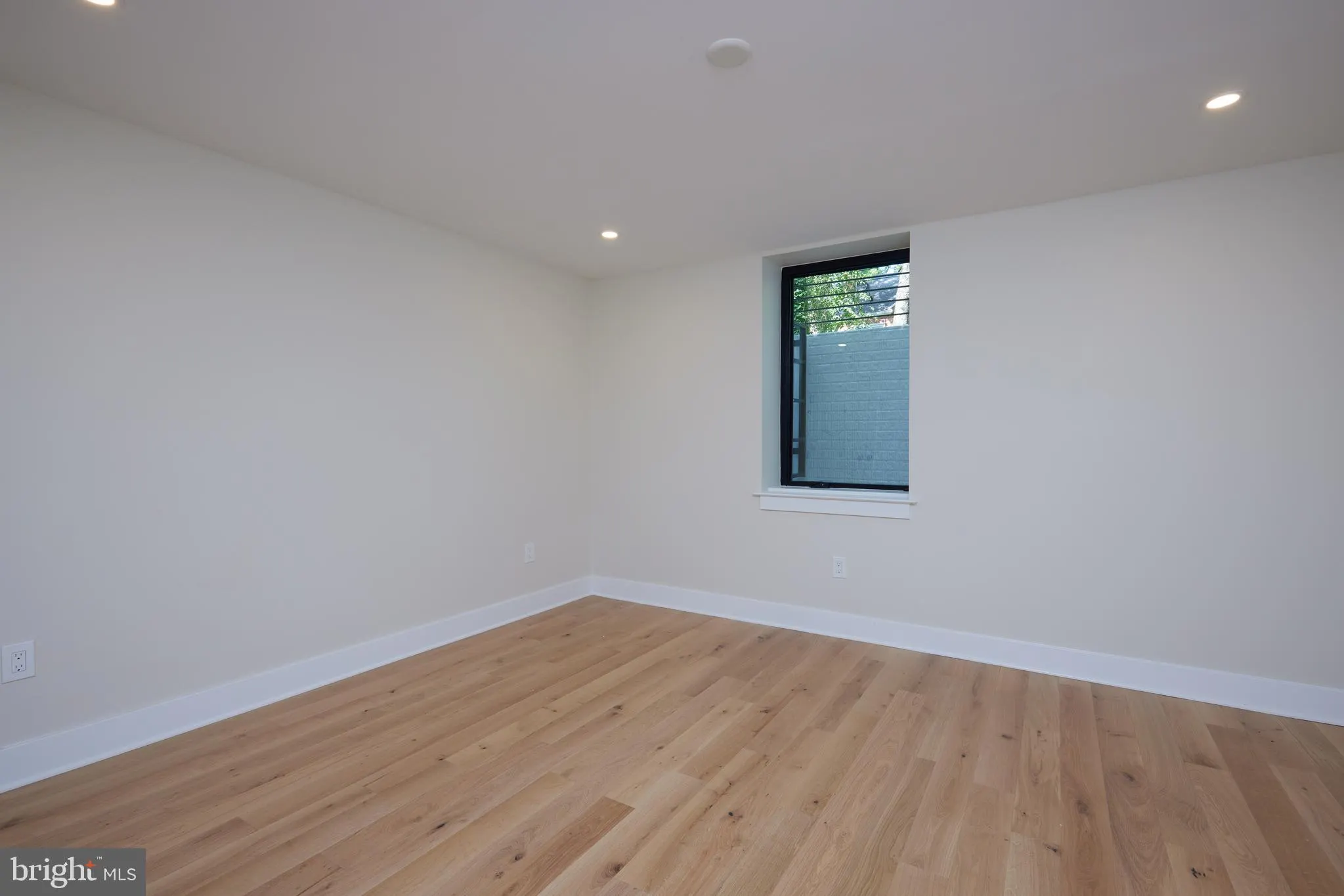 Empty bedroom with wood flooring and single window