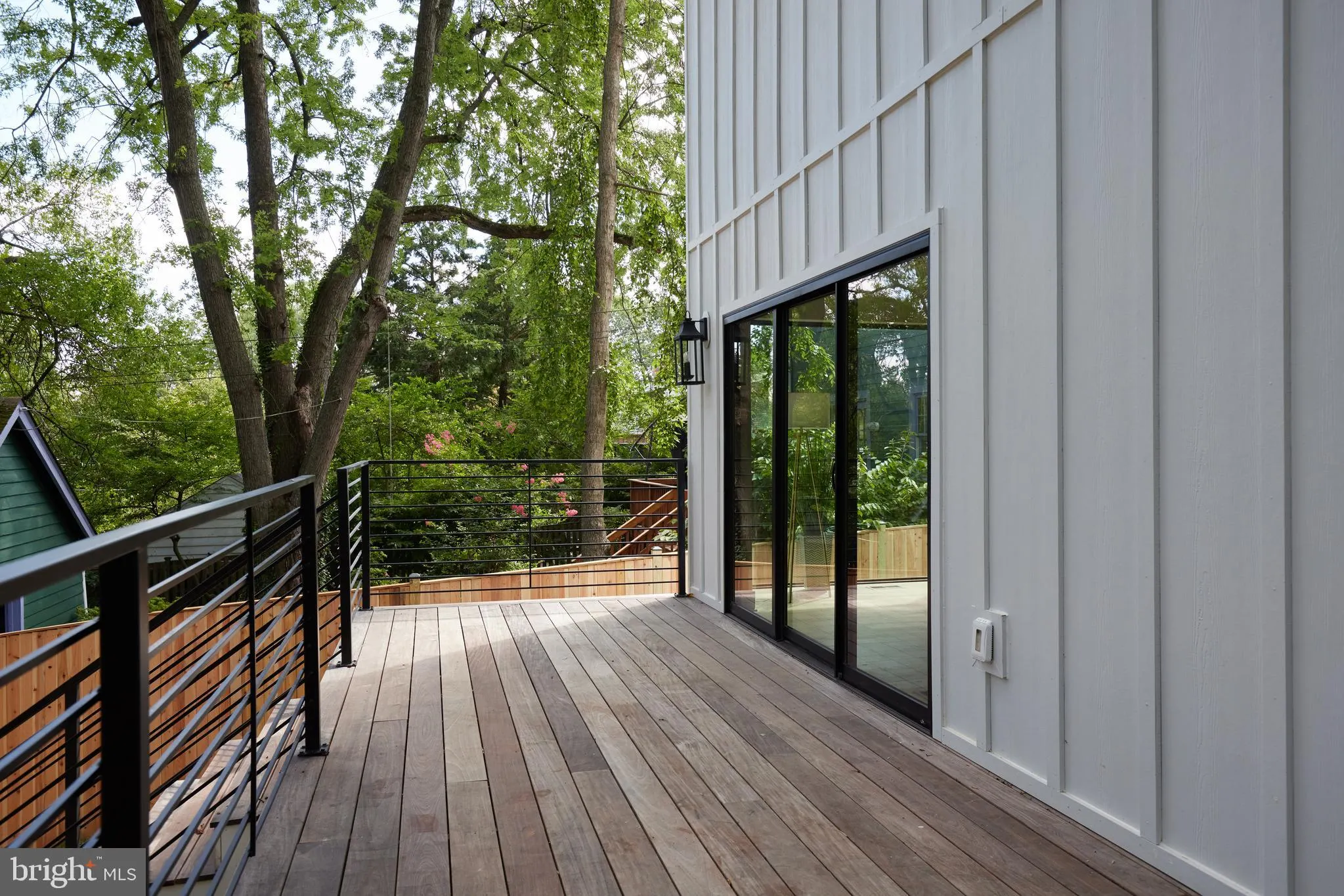 Deck with cable railing, glass doors, and forest views