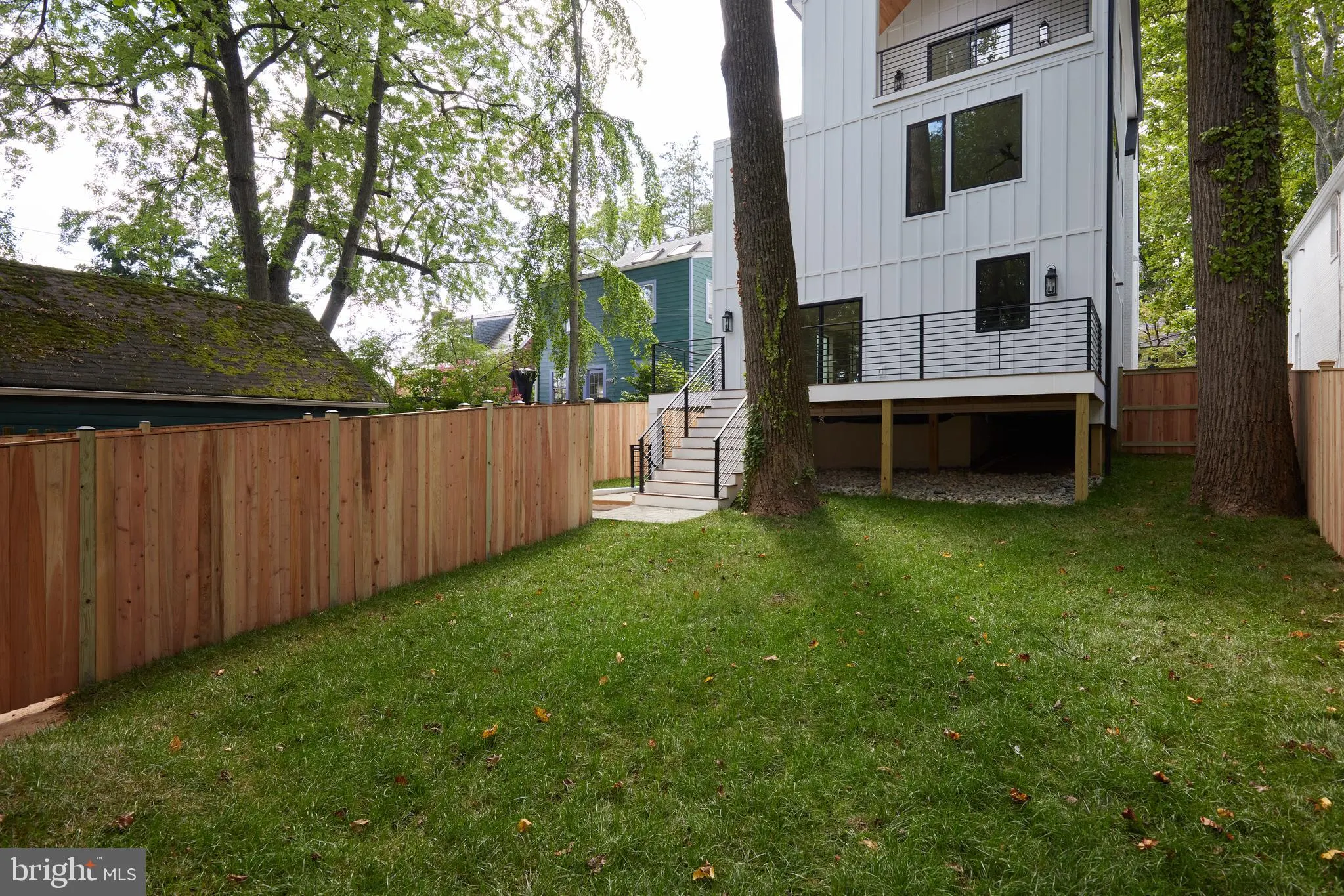 Modern house with backyard lawn and wooden privacy fencing