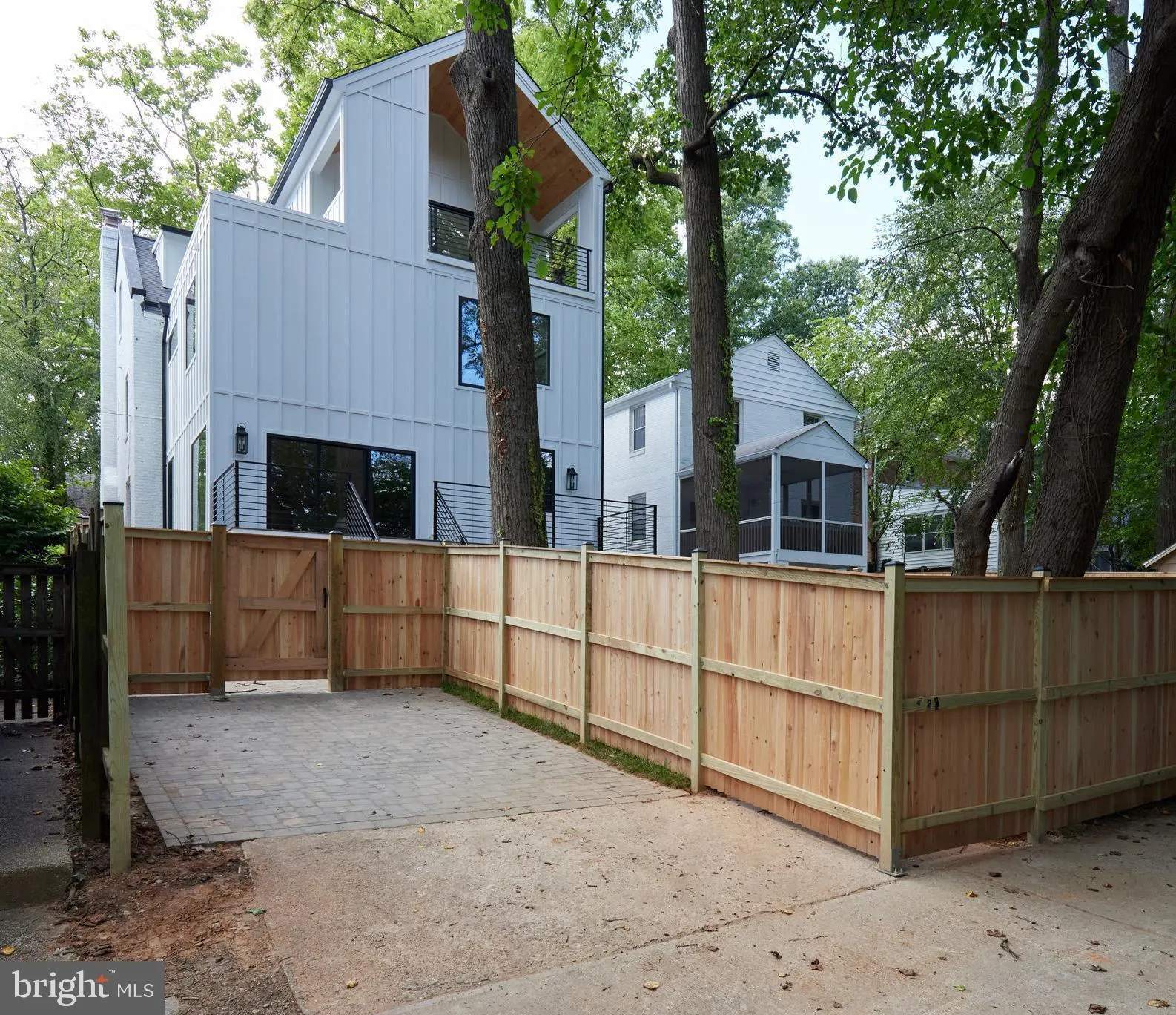 Modern white house with metal railing viewed from fenced courtyard