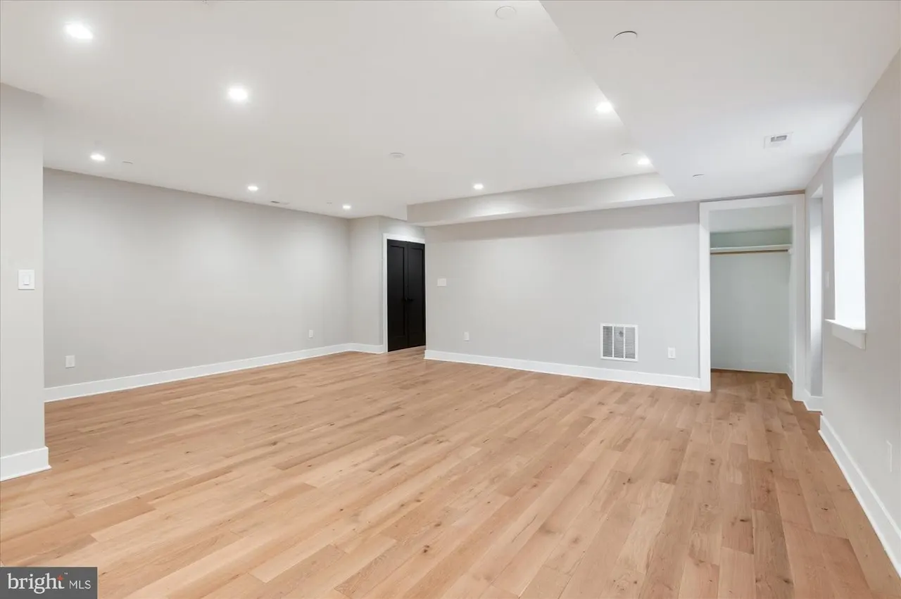 Empty recreation room with hardwood flooring and recessed lighting