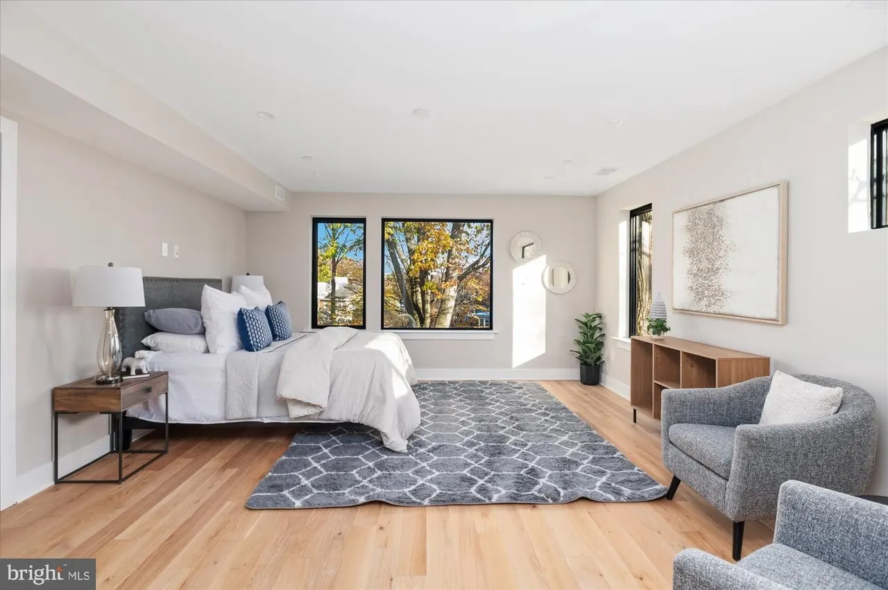 Primary bedroom with wood flooring, large windows, seating area