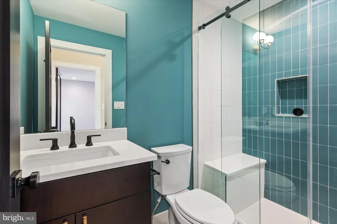 Bathroom with teal walls, white sink vanity, tiled shower