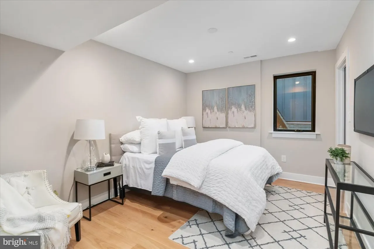 Primary bedroom with white bedding, blue accent pillow, and wood flooring