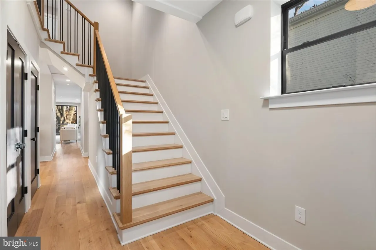 Foyer with wooden staircase and metal railing, hardwood floors