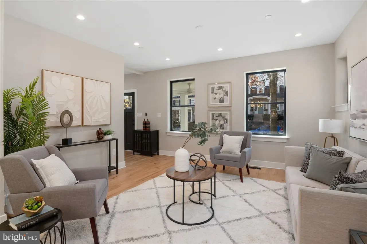 Open living room with gray seating, entryway console, and large windows