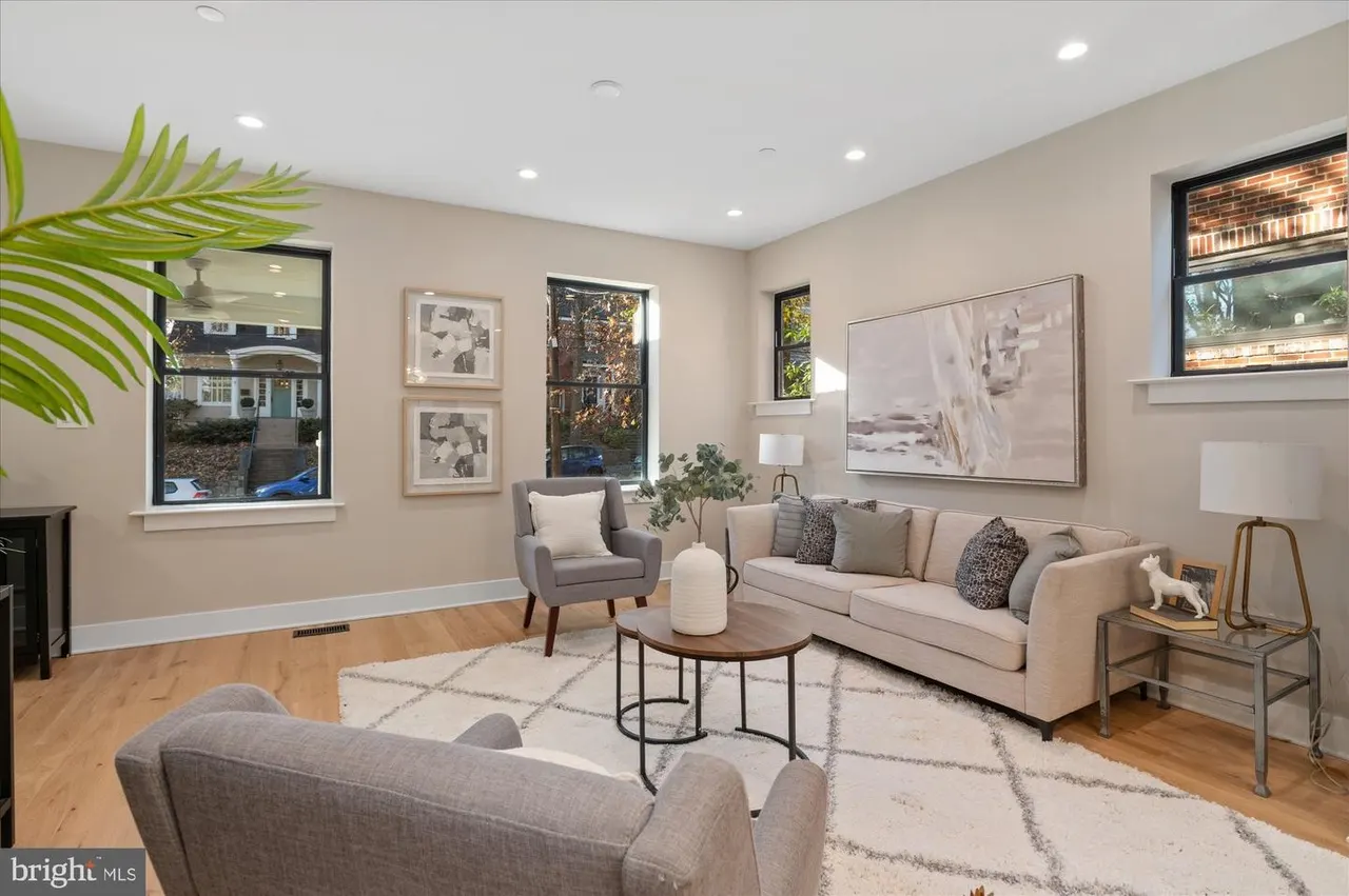 Living room with fireplace, cream sofa, gray armchair, and framed artwork