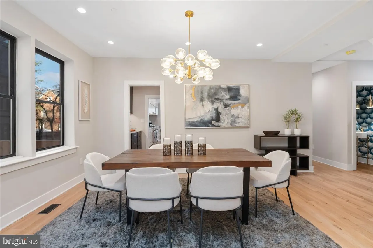 Dining room with wood table, white chairs, and brass globe pendant light