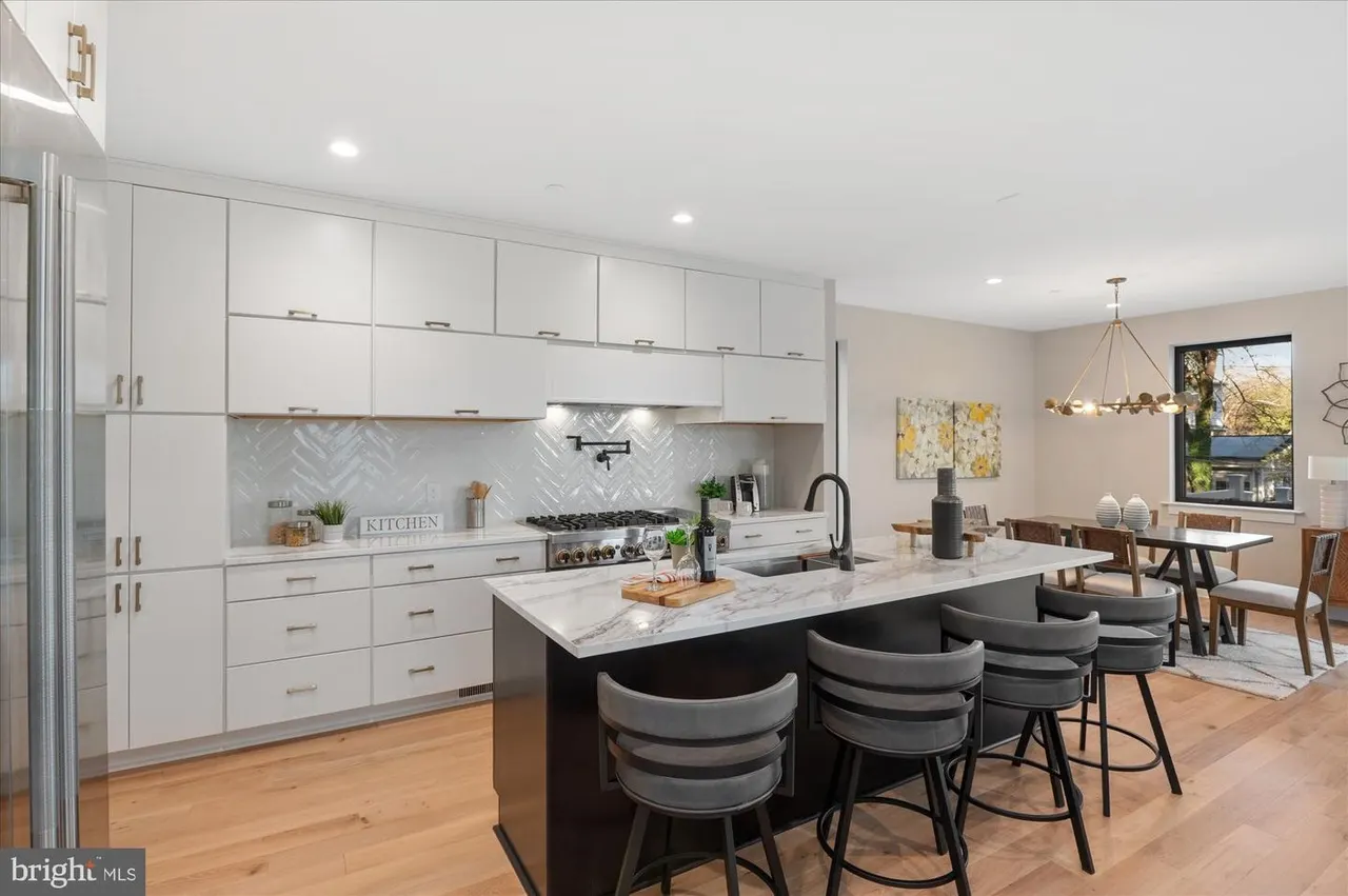 Kitchen with white cabinetry, marble island, and herringbone backsplash
