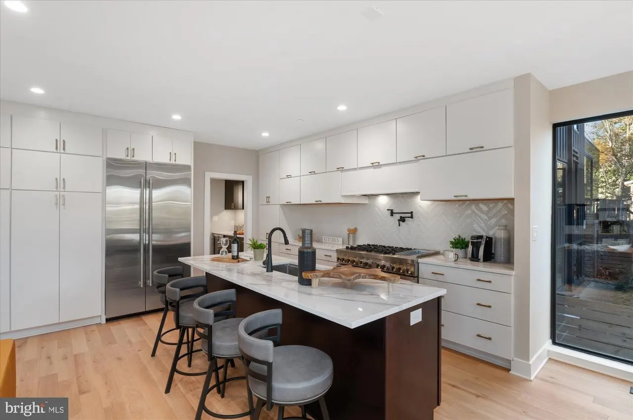 Kitchen with white cabinetry, black island, and stainless steel refrigerator