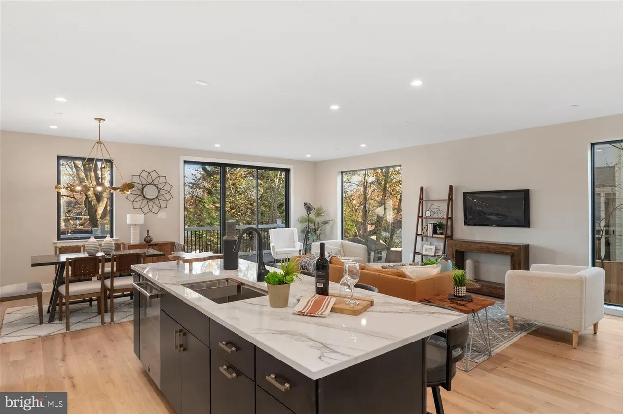 Great room with kitchen island, dining desk, orange sofa, and glass doors to patio