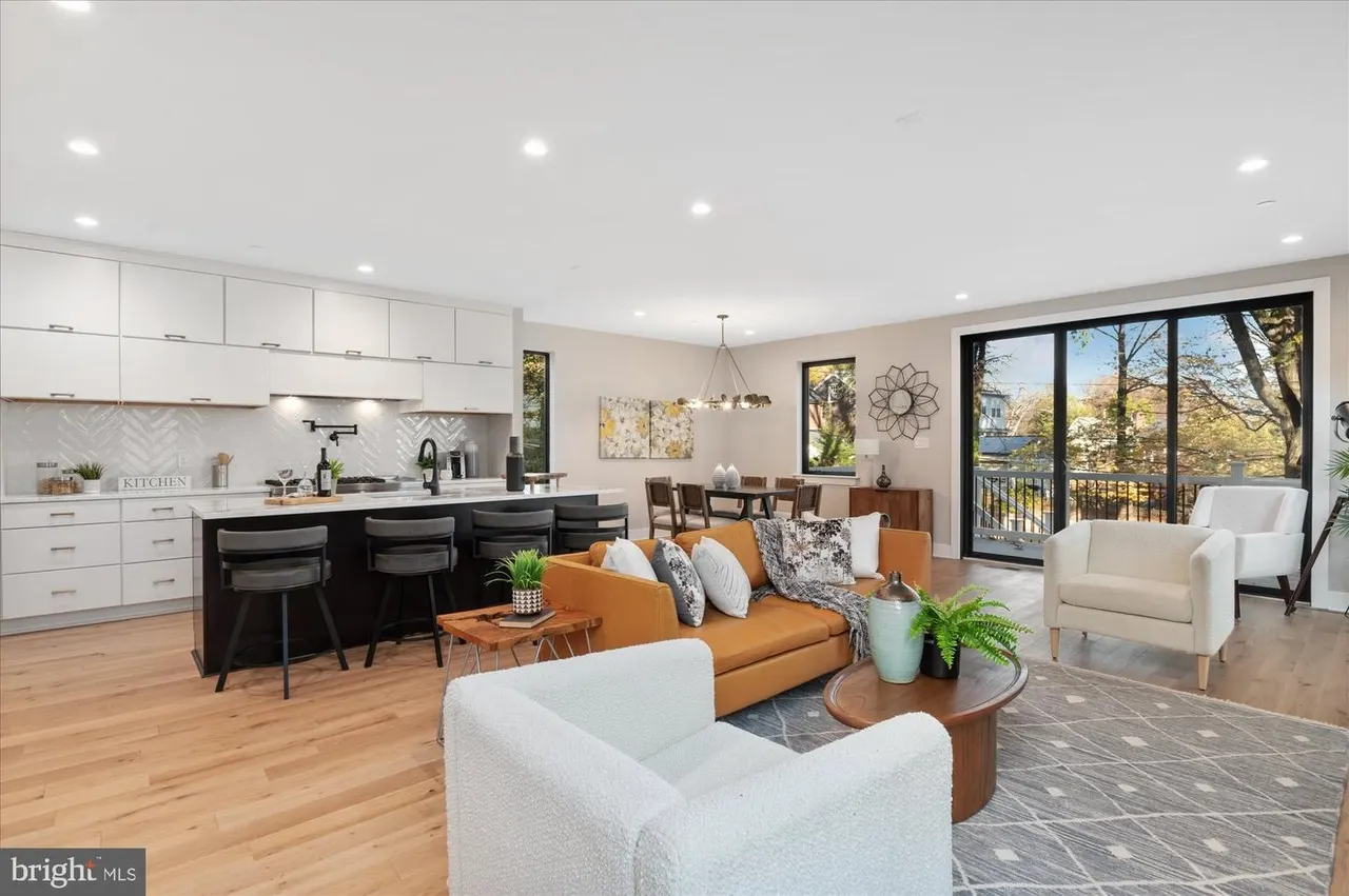 Open-concept kitchen, dining, and living space with white and dark cabinetry