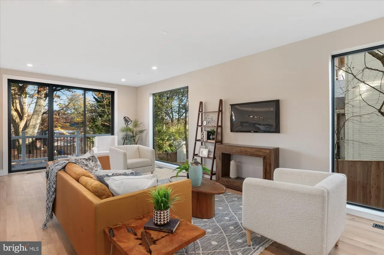 Living room with fireplace, orange sofa, white armchairs, and glass patio doors