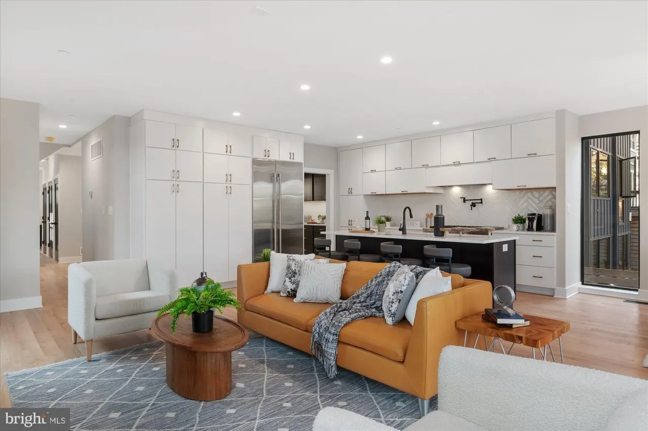 Open concept living area with orange sofa and white kitchen cabinetry