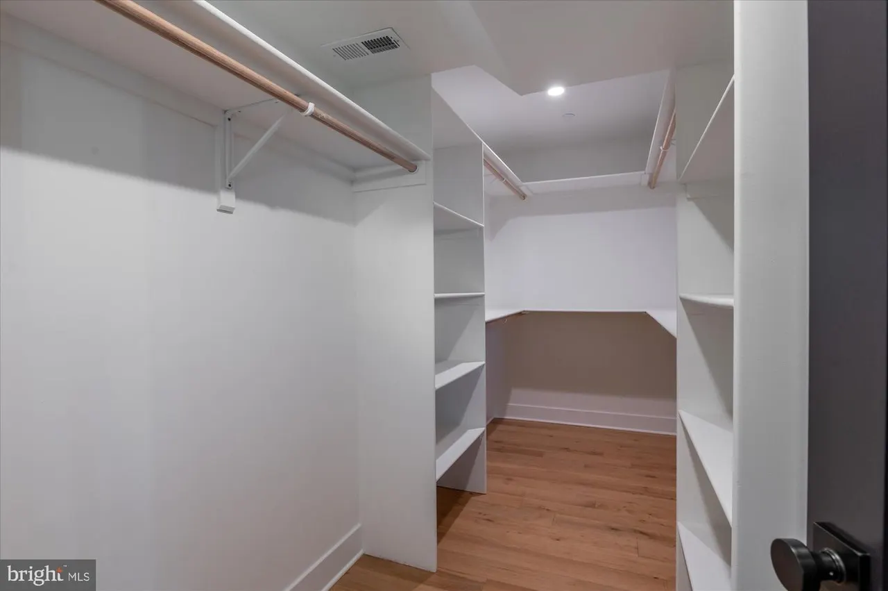 Large walk-in closet with built-in shelving and wooden rod