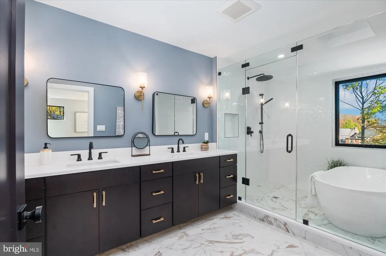 Primary bathroom with dark vanity, blue walls, and freestanding tub
