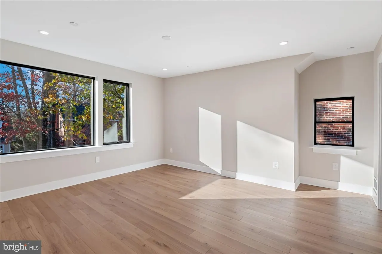 Empty room with wood floors and large windows overlooking trees