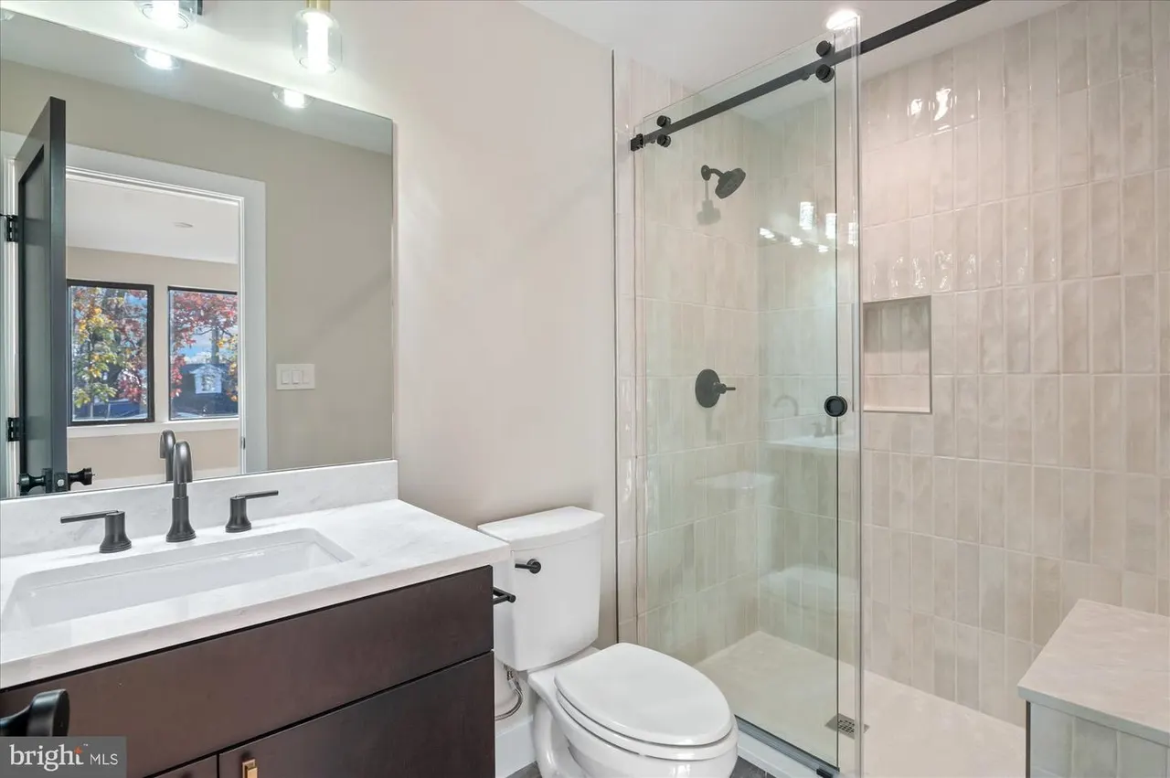 Bathroom with dark vanity, glass shower, and black fixtures