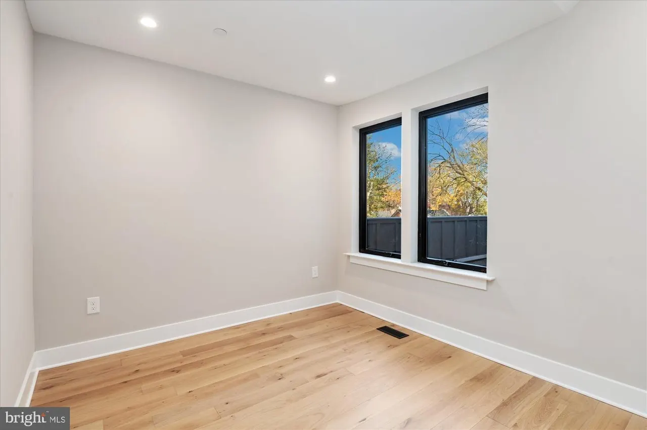 Bedroom with wood floors, windows, and white trim