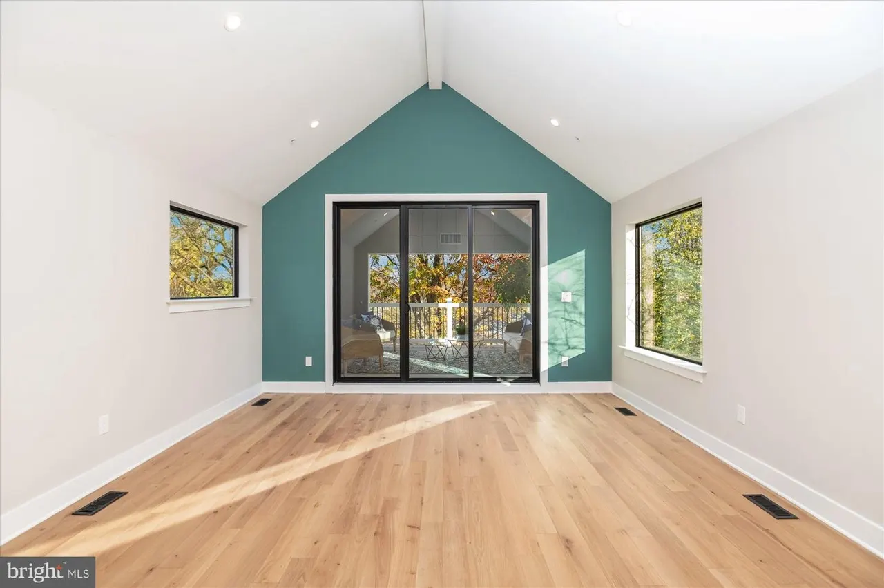 Room with teal accent wall, wood floors, and glass doors to deck