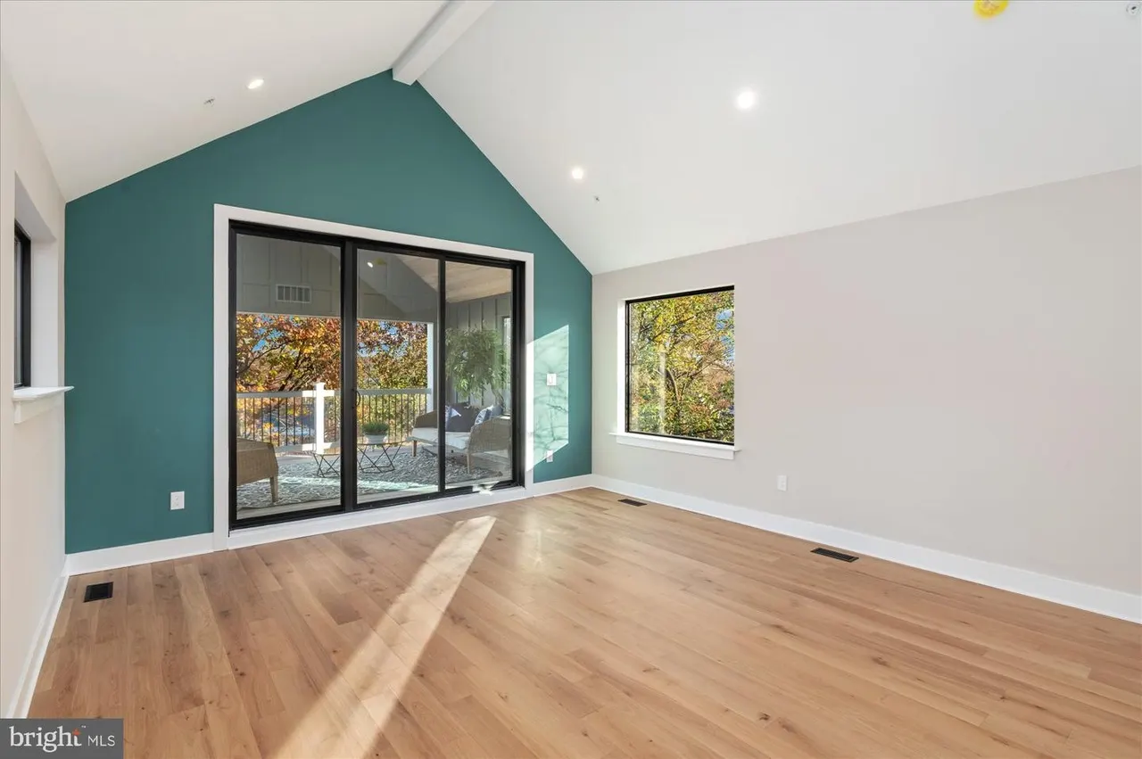 Room with teal accent wall, glass sliding doors, and wood flooring