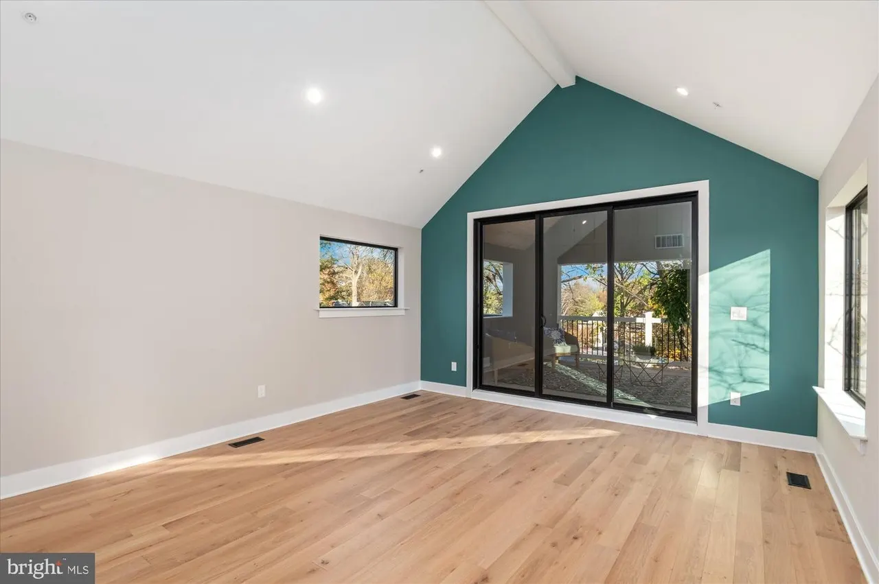 Open room with teal accent wall and sliding glass doors to deck