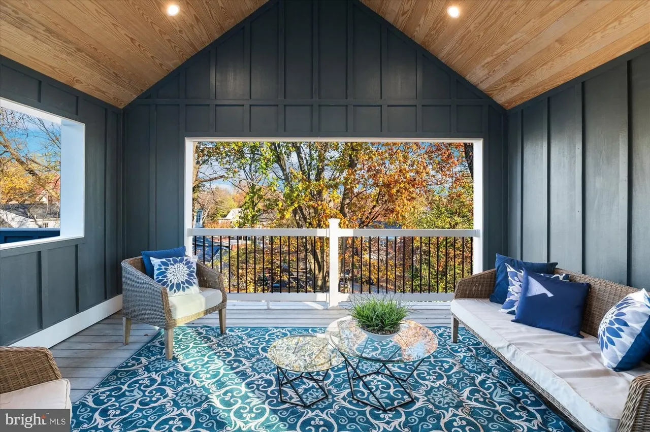 Screened porch with wooden ceiling, seating, and autumn tree views